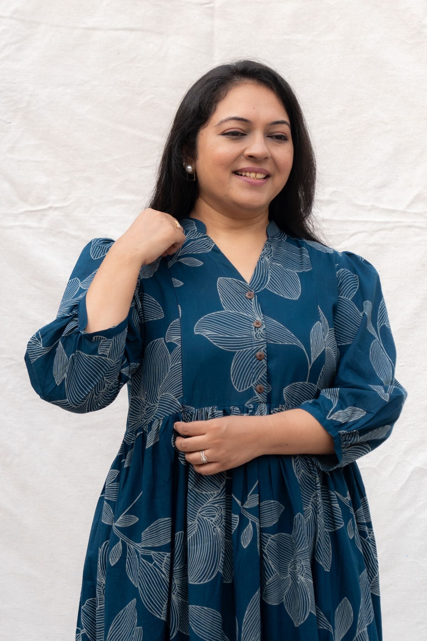 Woman wearing a blue dress with floral patterns against a white background