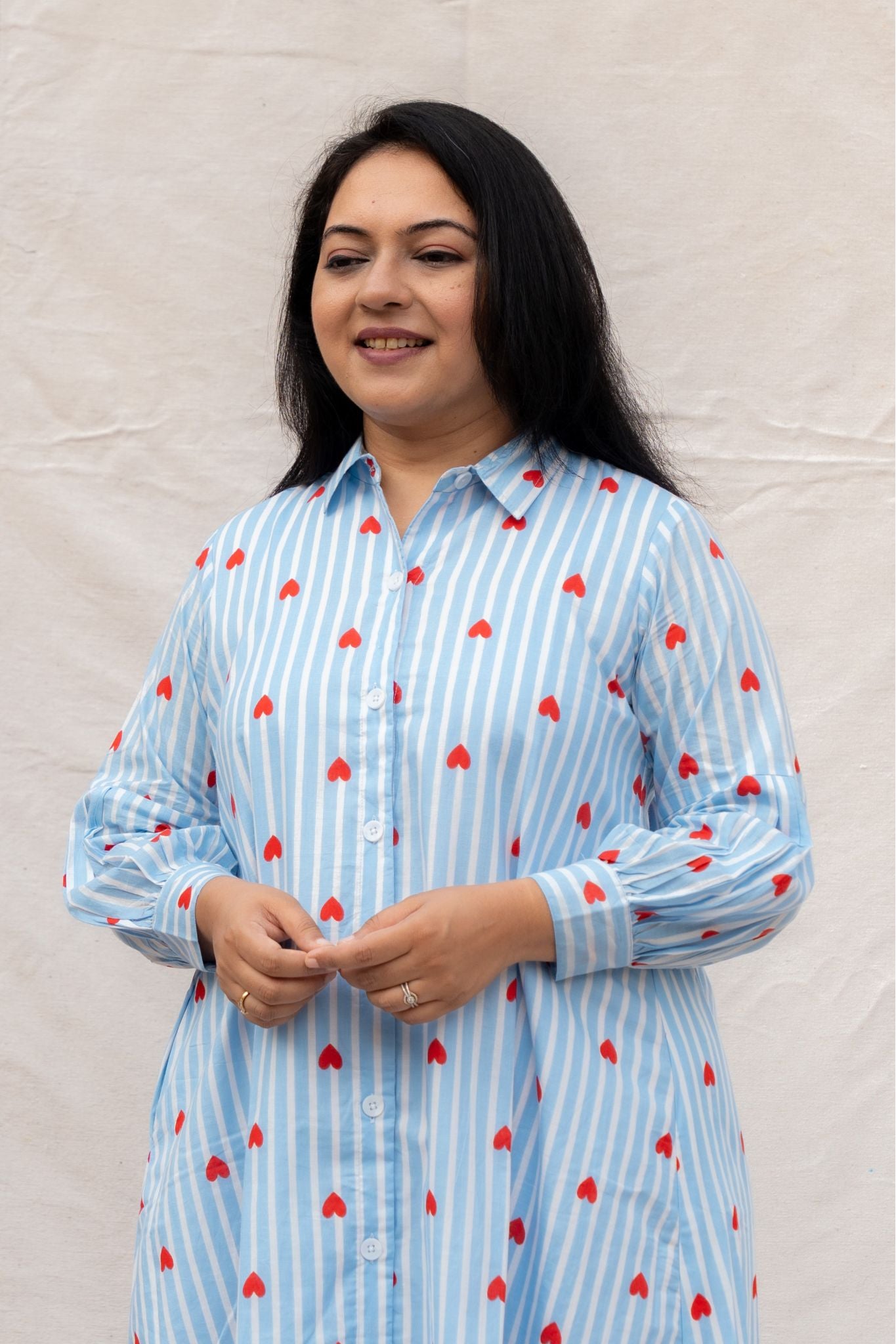 Woman wearing a blue striped shirt dress with red hearts patterns