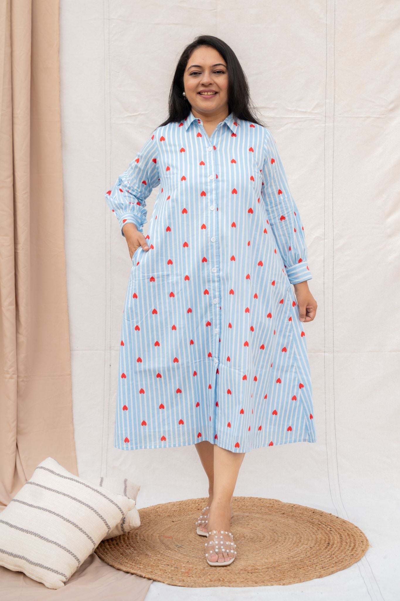 Woman wearing a blue striped shirt dress with red patterns on a beige background
