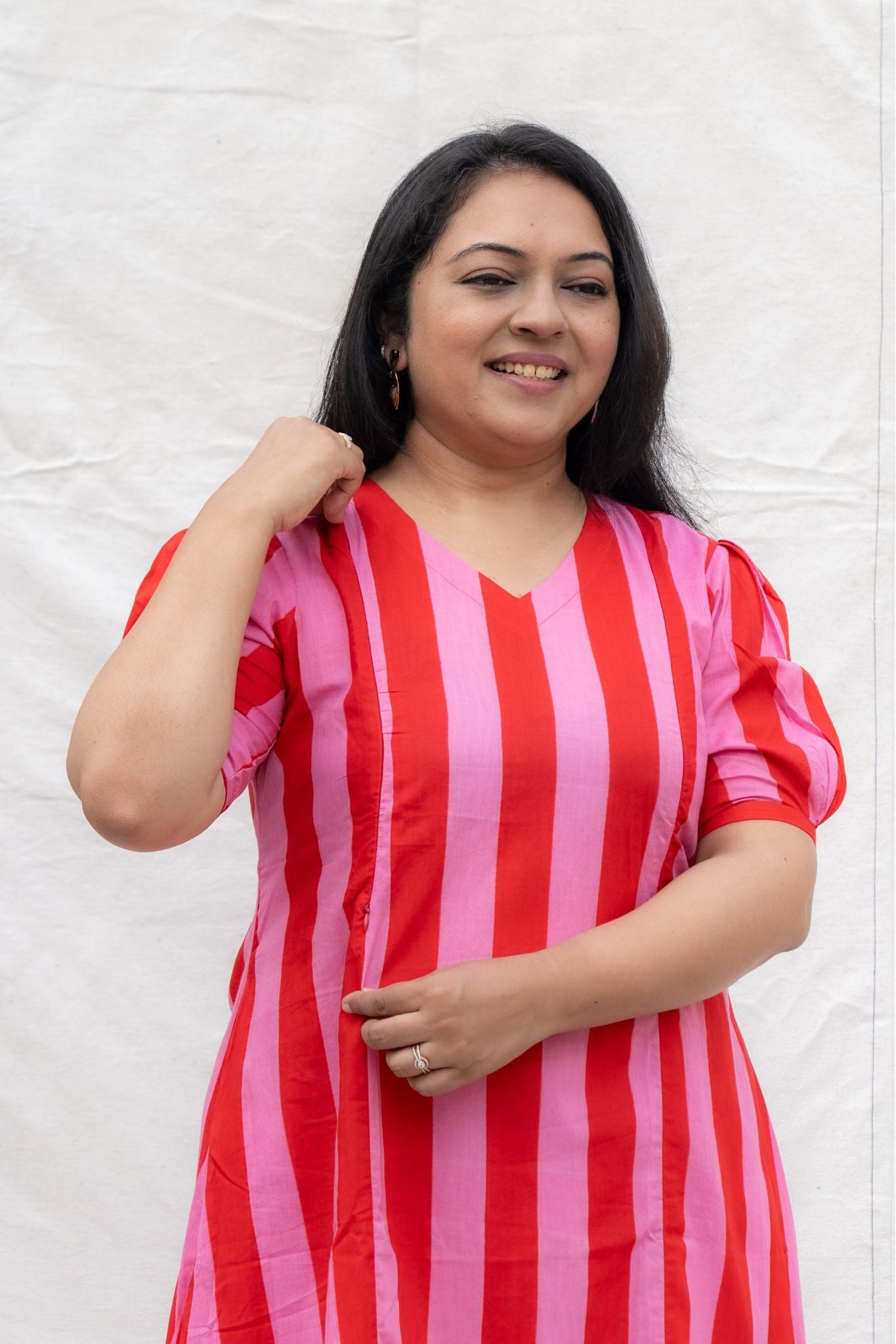 Woman wearing a red and pink striped dress against a white background
