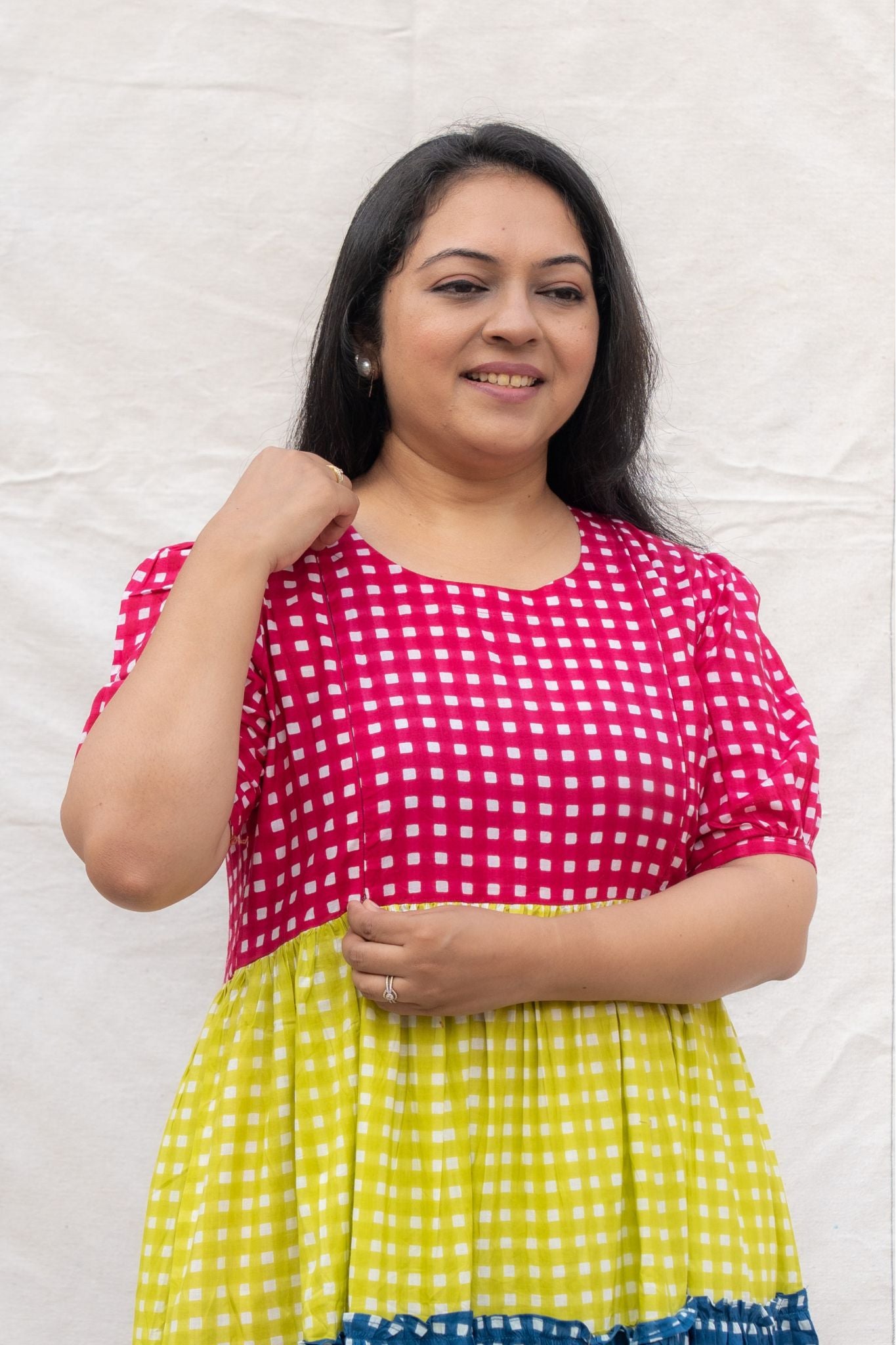 Woman wearing a pink and yellow checkered dress against a white background