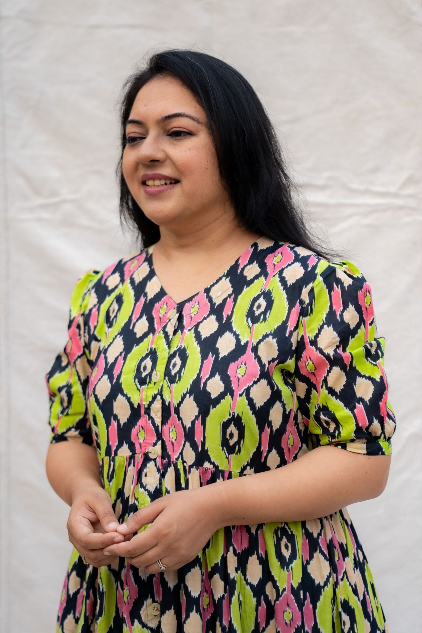 Woman wearing a colorful patterned dress against a plain background